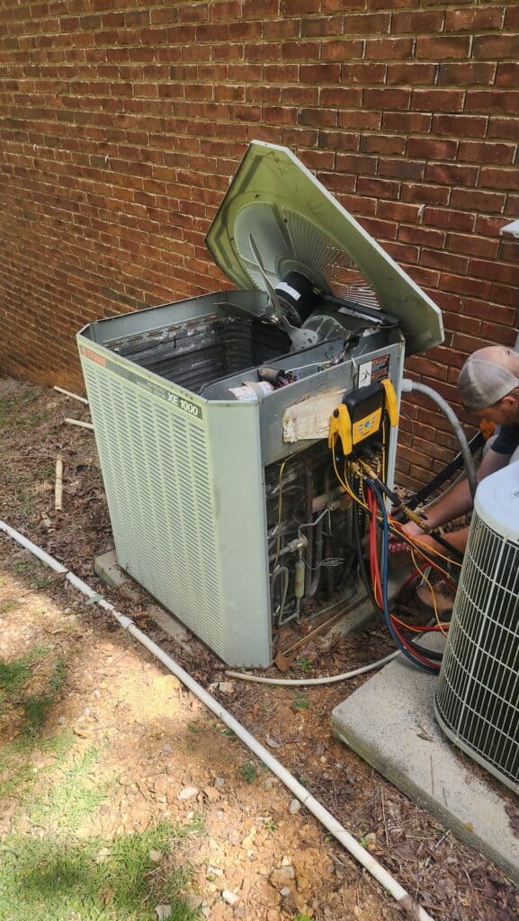 Older HVAC unit being repaired outside a brick building.