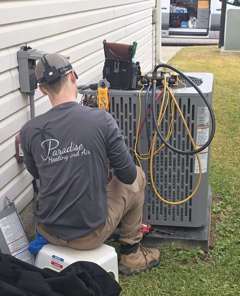 High-quality technician servicing HVAC unit outside residential building in Birmingham, AL.